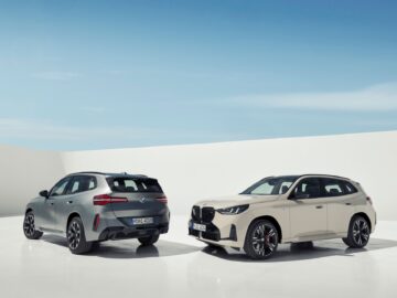 Deux SUV modernes sont garés sur un sol blanc sous un ciel bleu vif. L'un est une voiture argentée qui fait face à l'autre, l'autre est une BMW X3 2024 beige à essence et diesel, qui fait face à l'avant.