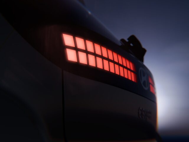 Nahaufnahme des Rücklichts eines Hyundai, das in der Dämmerung rot leuchtet. Zu sehen sind ein Gittermuster aus Lichtsegmenten und ein sichtbarer Teil der Karosserie des Autos.