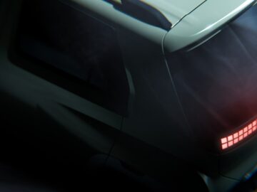 Eine Nahaufnahme der Rückleuchten und einer Ecke eines grauen Hyundai, die einen Teil der Rückleuchte und der Heckscheibe zeigt. Bei schwachem Licht scheint der Hyundai in Bewegung zu sein.