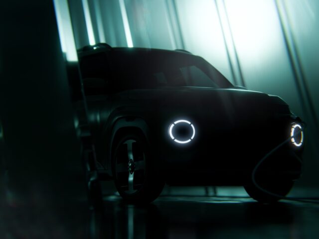 Una escena oscura que muestra un Hyundai parcialmente oscurecido, con dos faros redondos que brillan tenuemente en un entorno poco iluminado. La escena tiene una atmósfera futurista y misteriosa, que recuerda el enigmático encanto del modelo INSTER.