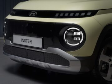 Close-up of the front end of a Hyundai INSTER EV price sticker with round headlights, a black grille and a license plate that reads 