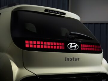 Achteraanzicht van een lichtgroene Hyundai INSTER met een gepixeld rood remlichtontwerp, met daarop de modelnaam "Inster", met bizarre specificaties die het tot een intrigerende EV-prijspakker maken.