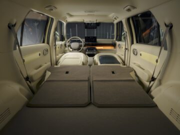 Inside view of a Hyundai INSTER with fully reclining rear seats, creating a flat cargo area that extends to the front seats and dashboard, perfect for those who appreciate unique and practical designs.