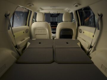 Binnenaanzicht van een Hyundai INSTER SUV met de achterbank neergeklapt, met uitgebreide laadruimte en beige lederen bekleding.