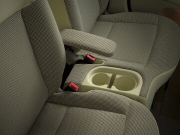 Vista aérea del asiento trasero del Hyundai INSTER EV, con un tejido estampado de pied-de-poule y un reposabrazos abatible con portavasos integrados.