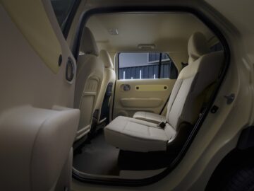 Vista interior de los asientos traseros del Hyundai INSTER, con tapicería de tela beige, asientos traseros abatidos y diseño minimalista de las puertas.