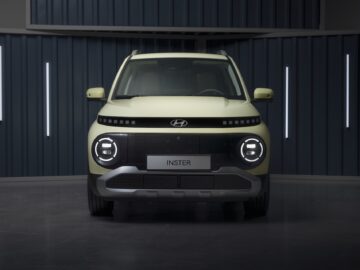 Vooraanzicht van een lichtgroene Hyundai INSTER-auto die binnen geparkeerd staat, met de koplampen en grille in de kijker, en voorzien van bizarre specificaties waardoor hij opvalt.