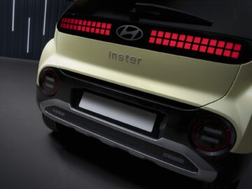 Achteraanzicht van een Hyundai-auto met het logo en de modelnaam "inster" in zilveren letters. Het ontwerp is voorzien van rode LED-verlichting en een zwart-wit kleurenschema, wat de strakke EV-esthetiek benadrukt.