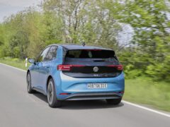 Een blauwe Volkswagen ID.3 elektrische auto met indrukwekkend rijbereik rijdt op een tweebaansweg omgeven door groen.