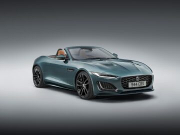 Een groene cabriolet Jaguar F-Type met lichtbruine stoelen wordt vanaf de voorkant getoond tegen een gradiëntgrijze achtergrond. Op het kenteken staat "944 CBS.
