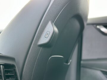 Close-up van de achterkant van een Kia Niro elektrische bestuurdersstoel met een elektrische verstelknop en ventilatieopening.
