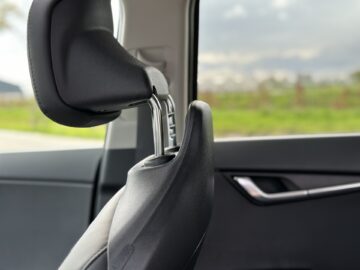 Close-up van de hoofdsteun van een Kia Niro Electric-autostoel met een wazig buitentafereel zichtbaar door het raam op de achtergrond.