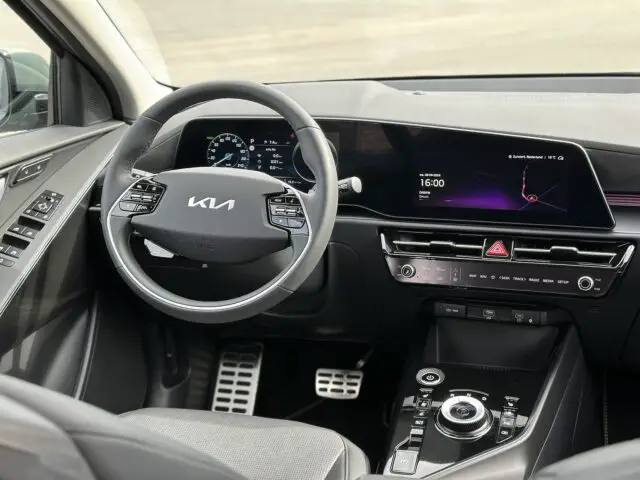 Stuur en dashboard van een modern elektrisch Kia Niro-voertuig, met een digitaal display, verschillende bedieningselementen en een strak interieurontwerp.