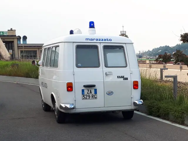 Een wit Fiat busje, bekend van de klassieke Fiat modellen en voorzien van het opschrift "marazzato" met kenteken ZA 329 RC, staat geparkeerd op een weg. Met blauwe lichten op het dak en het woord "AUTOSO" gedeeltelijk zichtbaar op de zijkant, is het een zeldzame verschijning in het verkeer.