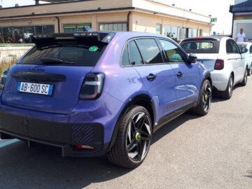 Een paarse Lynk & Co 05-auto met kenteken AB-600-SC staat op een zonnige dag in een file achter een witte auto geparkeerd, wat doet denken aan de klassieke lijnen die je ziet in klassieke Fiat-modellen. Gespot op zo'n bruisende middag!