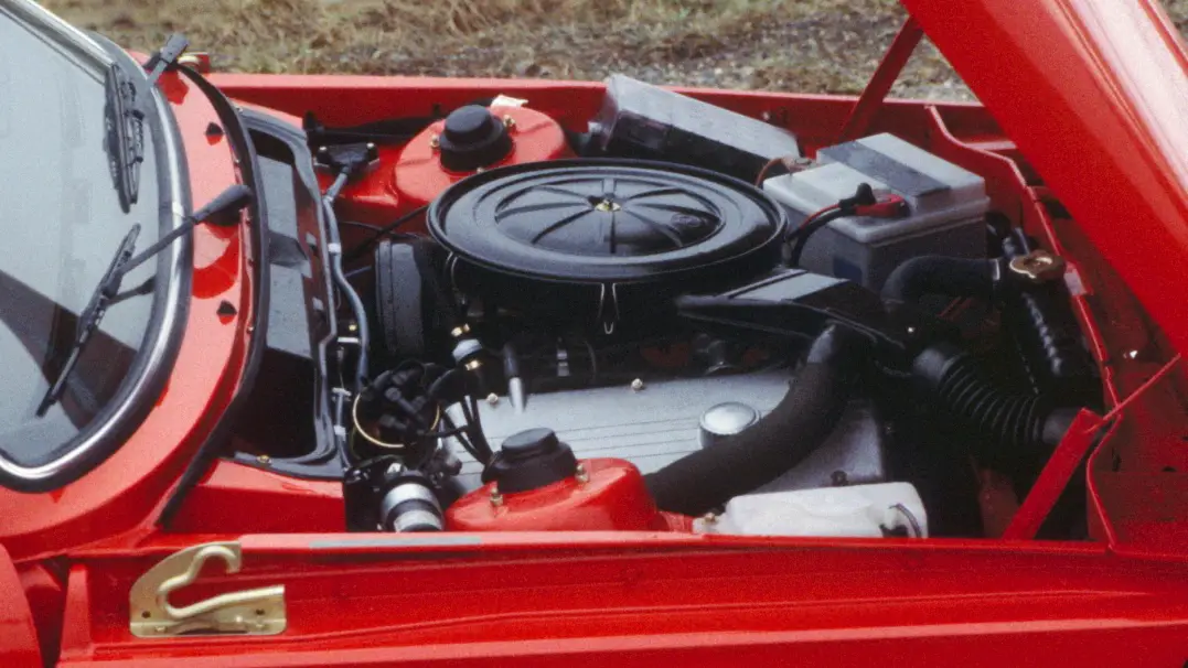 Primer plano del capó de un coche abierto, mostrando el motor y diversos componentes de un primitivo BMW 316, mostrando el meticuloso diseño de este icónico vehículo rojo.