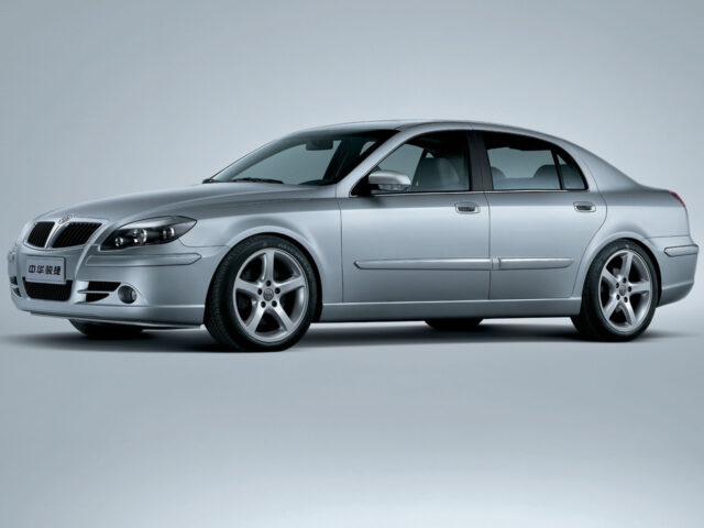 A silver-colored Brilliance BS4 sedan with a sleek design is spotted on a plain gray background. The vehicle features four doors, alloy wheels and an elegant front grille.