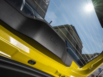 Gros plan sur le hayon arrière à l'intérieur d'une Fiat Grande Panda jaune. La lumière du soleil pénètre par la lunette arrière dans l'extérieur de la voiture et met en valeur l'intérieur bien conçu.