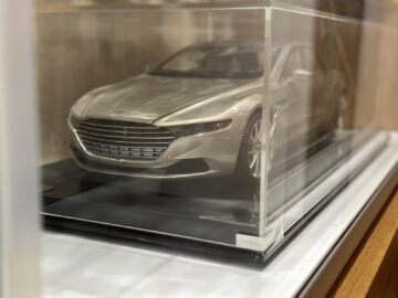 Un primer plano de un modelo plateado de Aston Martin, expuesto en un estuche de acrílico transparente, que muestra las vistas frontal y lateral, según el último reportaje fotográfico del Heritage Trust Museum.