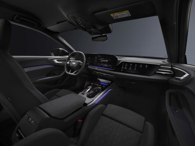 Interior view of a modern Audi A5 featuring a sleek dashboard with a large central display, illuminated accents, steering wheel and front seats.