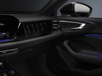 Interieur van een Audi A5 met de kenmerken van een moderne auto, zoals een digitaal dashboard, touchscreenbediening, deurgreep en zijspiegel.