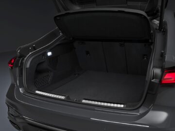 The open trunk of an Audi A5 reveals a spacious, empty cargo area with a dark interior and a small light on the side.