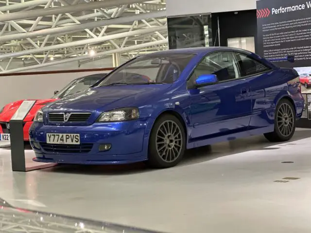 Een blauwe Vauxhall Astra coupé met een "Y774 PVS" kentekenplaat is te zien in de showroom van het British Motor Museum.