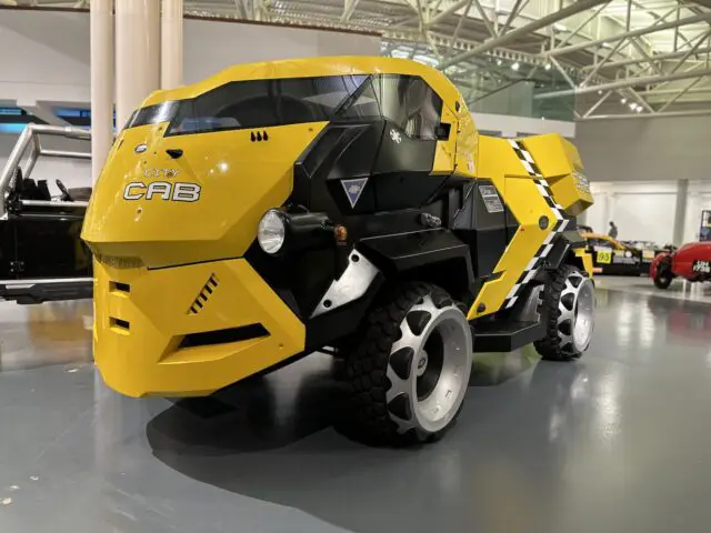 Een geel-zwart conceptvoertuig genaamd "City Cab" is binnen te zien in het British Motor Museum, met industriële designelementen en grote offroad-banden.