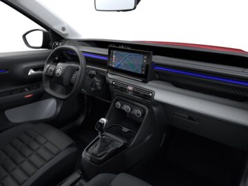 Interieur van een moderne auto met een aanraakscherm met navigatie, een handmatige versnellingspook en een strak dashboardontwerp met blauwe sfeerverlichting; doet denken aan de Uitrusting Citroën C3.