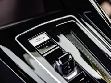 Close-up of a VW Golf's start-stop engine button and shifter on a glossy black panel.