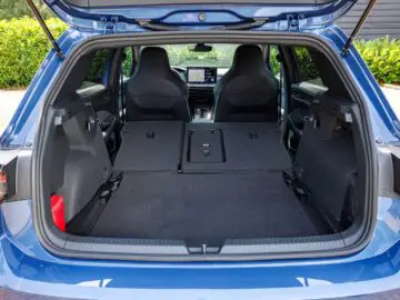 Open kofferbak van een blauwe VW Golf SUV met daarin een ruime bagageruimte met de achterbank neergeklapt, waardoor er voldoende opbergruimte ontstaat. Op de achtergrond zijn de voorstoelen en het dashboardscherm zichtbaar.