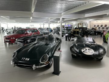 A Trust collection of vintage and classic cars displayed in an indoor showroom, featuring a green sports car with 