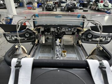 Een auto die wordt geassembleerd in een autowerkplaats, met het interieur en de deuren open, waardoor de mechanische en elektronische componenten erin zichtbaar worden.