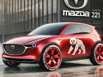 Un prototipo Mazda 221 rojo con la imagen de un oso en el lateral está aparcado delante de un edificio con un gran logotipo de Mazda, siguiendo el espíritu de su predecesor, el Mazda 121. El coche tiene unas llamativas llantas rojas con letras blancas en los neumáticos.