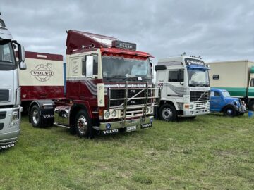 Een opstelling van drie Volvo-trucks te zien in een grasveld op een bewolkte dag tijdens de West Oxon Steam & Vintage Show 2024.