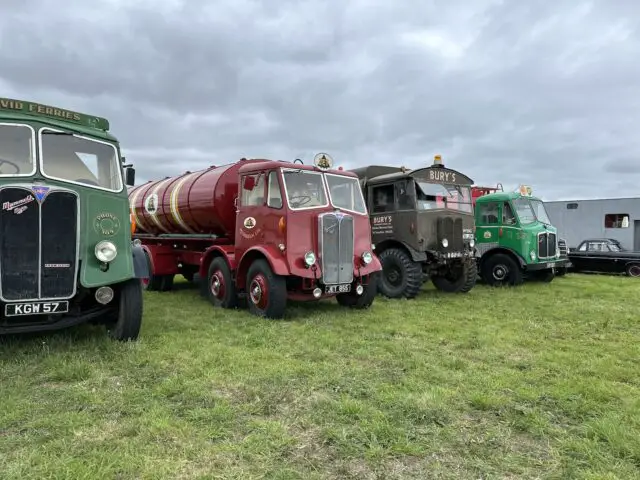 Een reeks vintage vrachtwagens tentoongesteld op een grasveld onder een bewolkte hemel tijdens de West Oxon Steam & Vintage Show 2024.