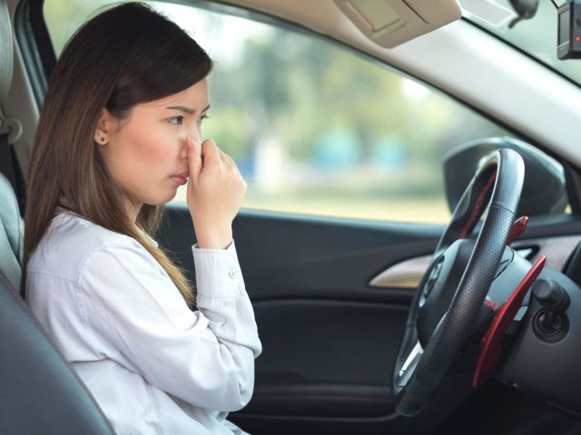 Young woman holding her nose because of bad smell in car ...